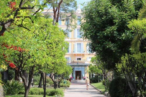 Hôtel L'Orangeraie surrounded by trees and palms